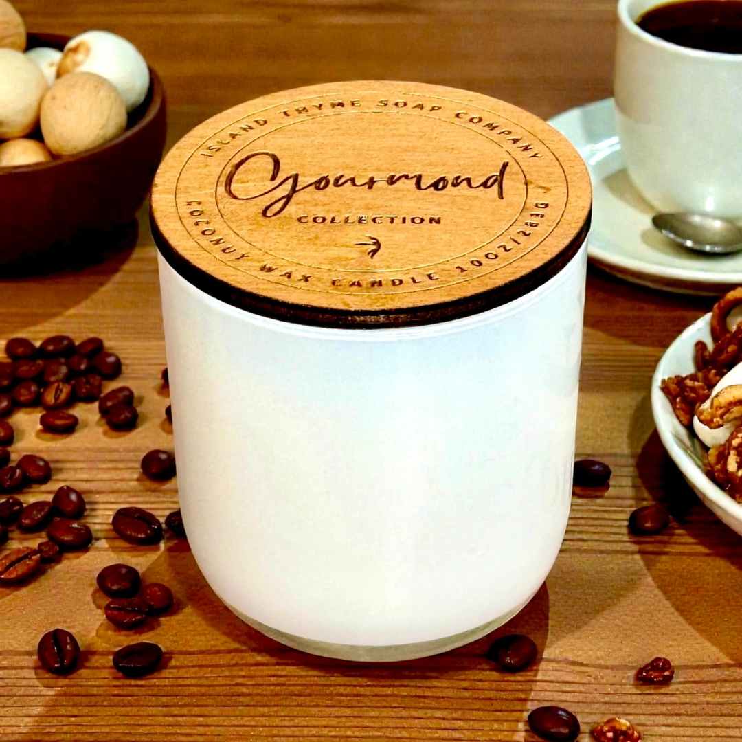 White glass candle with wooden lid on a table with coffee beans and a cup of coffee