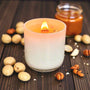 Candle in a glass holder with star-shaped cookies and a bottle of oil on a wooden surface.