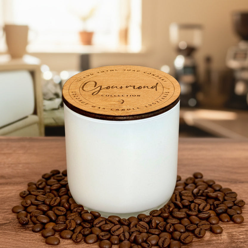 White candle with a wooden lid on a wooden surface, featuring 'Gourmand' collection branding.